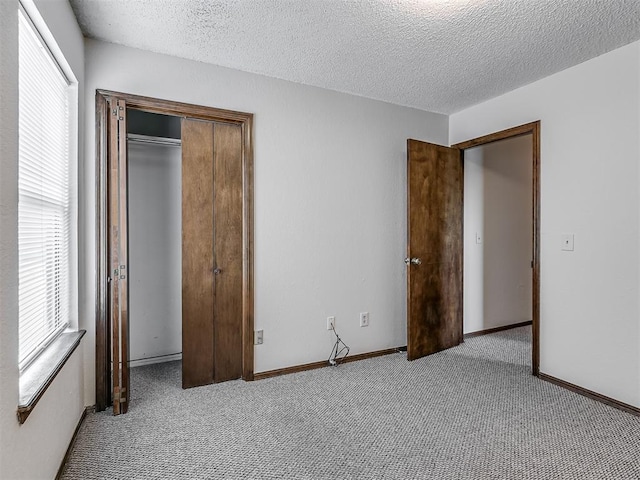 unfurnished bedroom with a closet, baseboards, carpet, and a textured ceiling