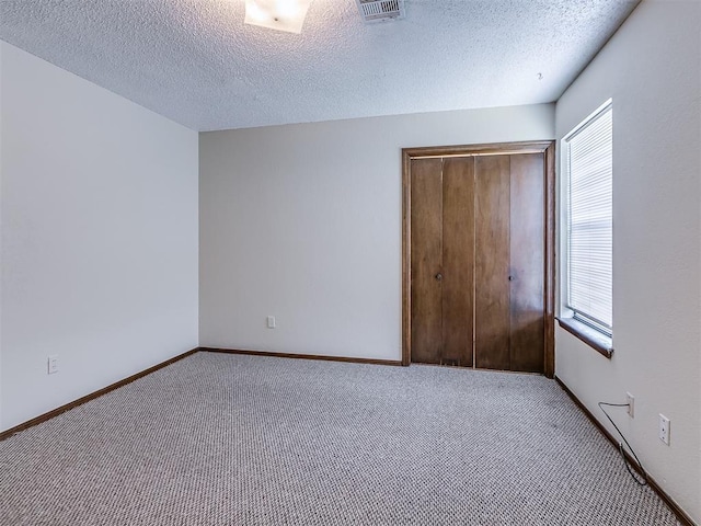 unfurnished bedroom featuring carpet floors, multiple windows, a closet, and visible vents