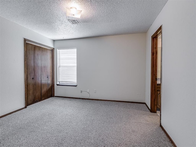 unfurnished bedroom featuring a closet, carpet flooring, visible vents, and a textured ceiling