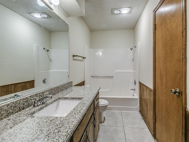 bathroom with a textured ceiling, vanity, toilet, washtub / shower combination, and tile patterned floors