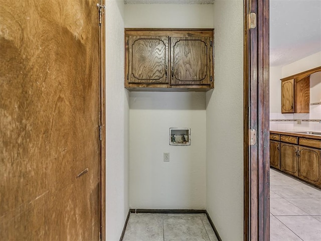 washroom featuring light tile patterned floors, washer hookup, and cabinet space