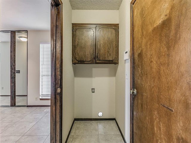 washroom featuring cabinet space, baseboards, hookup for an electric dryer, and light tile patterned flooring