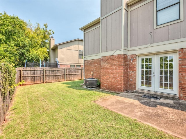 view of yard with french doors, a fenced backyard, and cooling unit
