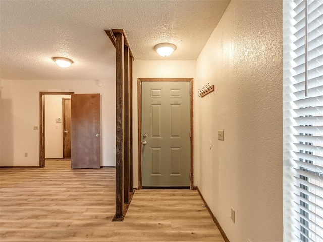 interior space featuring light wood-style flooring, baseboards, and a textured ceiling