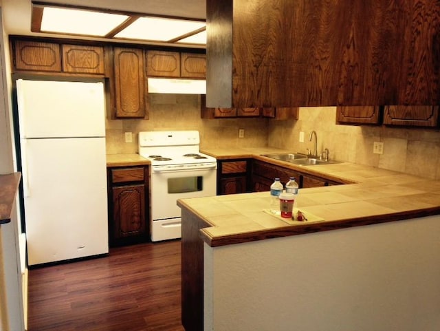 kitchen featuring range hood, a sink, white appliances, dark wood finished floors, and tile countertops