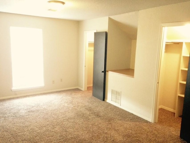 unfurnished bedroom featuring a closet, a spacious closet, visible vents, carpet flooring, and baseboards