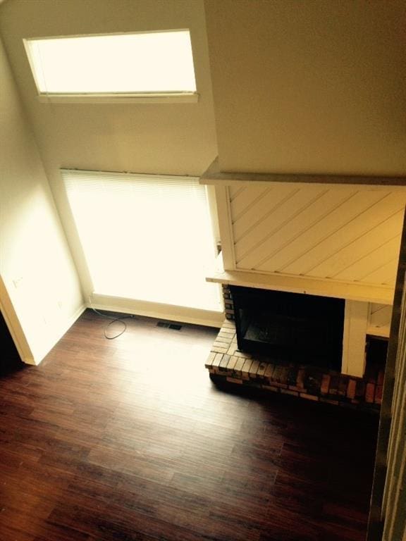 unfurnished living room featuring dark wood-type flooring, baseboards, and a wealth of natural light