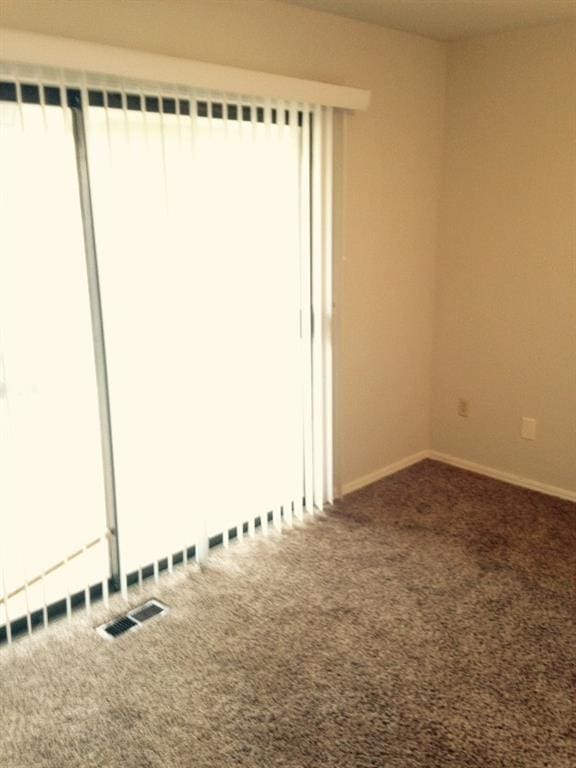 carpeted spare room with visible vents and baseboards
