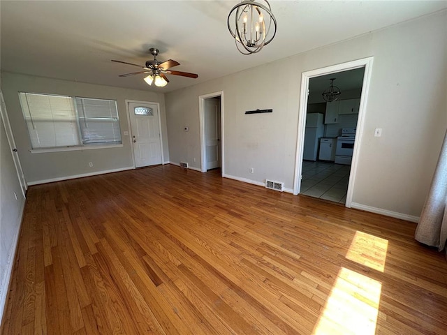 4445 NW 19th St, Oklahoma City, OK 73107 - unfurnished living room with visible vents, baseboards, light wood-type flooring, and ceiling fan with notable chandelier