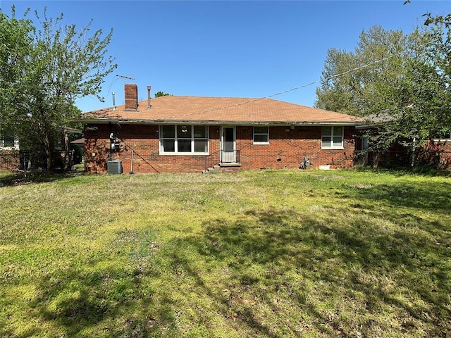 4445 NW 19th St, Oklahoma City, OK 73107 - back of house featuring brick siding, a chimney, a lawn, and central air condition unit