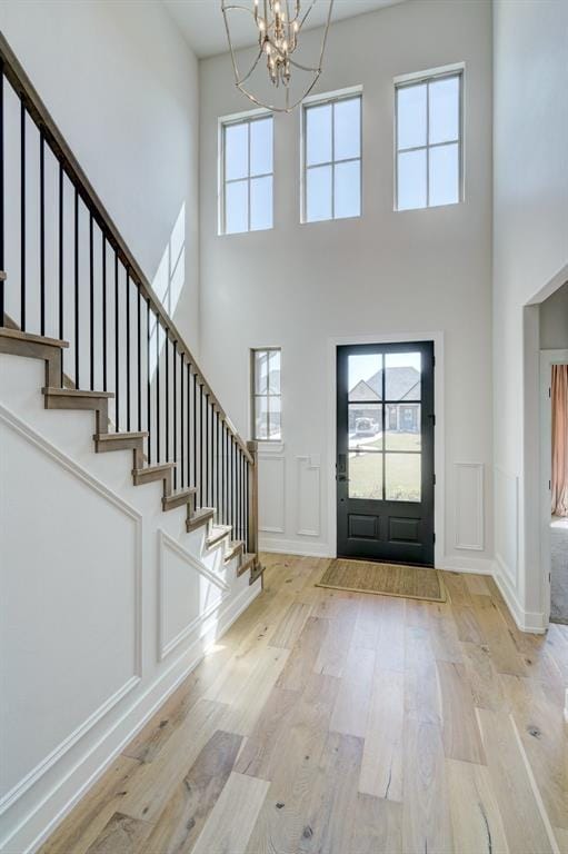 101 Pont Neuf Ct, Edmond, OK 73034 - foyer with a decorative wall, stairway, a chandelier, wood finished floors, and a high ceiling