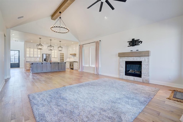101 Pont Neuf Ct, Edmond, OK 73034 - living room featuring ceiling fan with notable chandelier, light wood-style flooring, a stone fireplace, visible vents, and beam ceiling