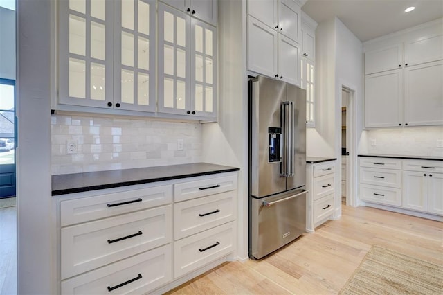 101 Pont Neuf Ct, Edmond, OK 73034 - kitchen featuring glass insert cabinets, high quality fridge, dark countertops, light wood-style floors, and decorative backsplash