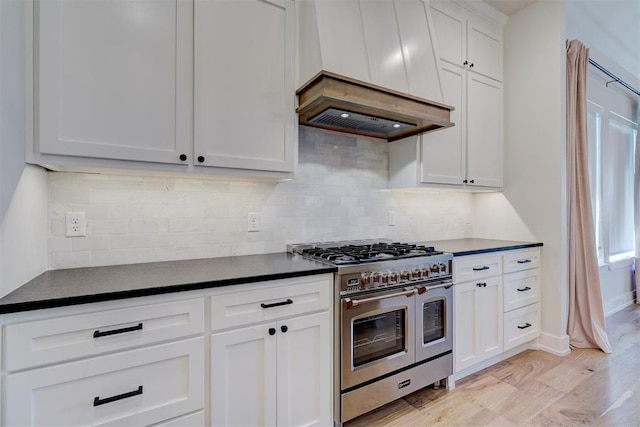 101 Pont Neuf Ct, Edmond, OK 73034 - kitchen with light wood-style flooring, white cabinetry, premium range hood, dark countertops, and range with two ovens