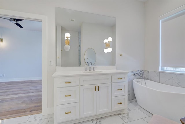 101 Pont Neuf Ct, Edmond, OK 73034 - bathroom featuring ceiling fan, a freestanding tub, vanity, marble finish floor, and baseboards