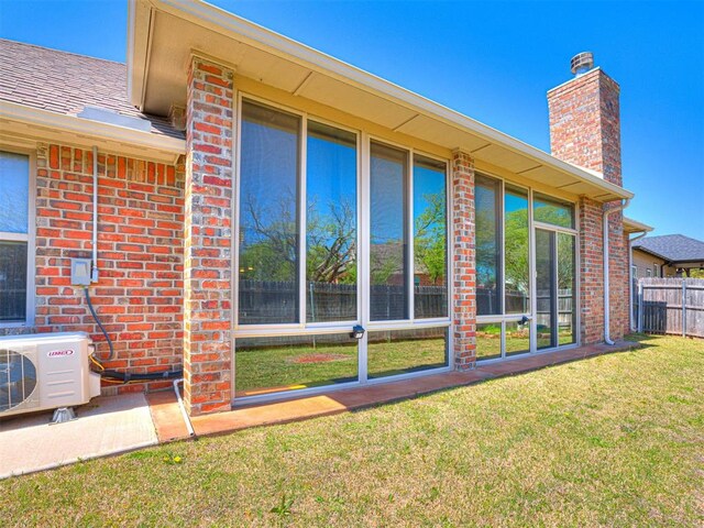 back of property with brick siding, a chimney, fence, and ac unit