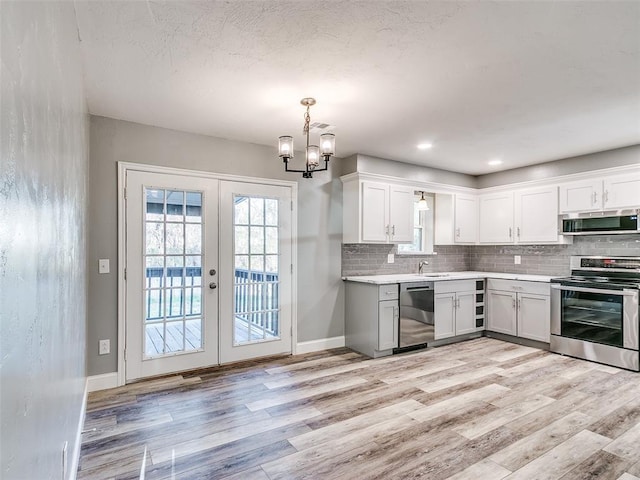 kitchen with light wood-style flooring, appliances with stainless steel finishes, decorative backsplash, and light countertops