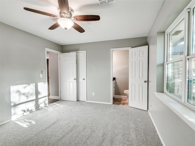 unfurnished bedroom with baseboards, multiple windows, and carpet flooring