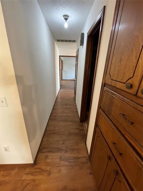 809 Tottingham Rd, Anadarko, OK 73005 - hall featuring visible vents, wood finished floors, and a textured ceiling