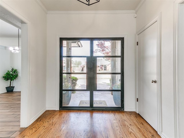 doorway to outside featuring ornamental molding, baseboards, and light wood-type flooring