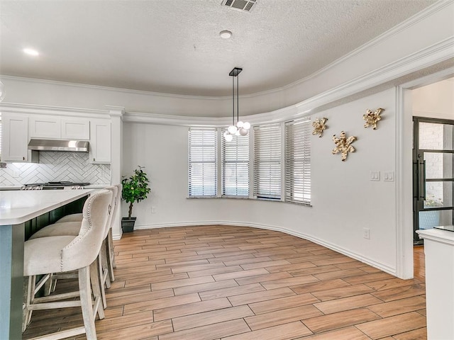 dining area with ornamental molding, plenty of natural light, a notable chandelier, and light wood-style floors