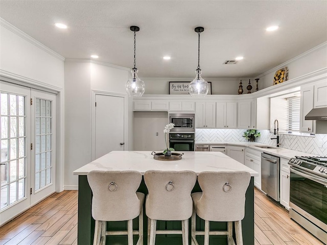 kitchen with a kitchen island, visible vents, decorative backsplash, stainless steel appliances, and a sink