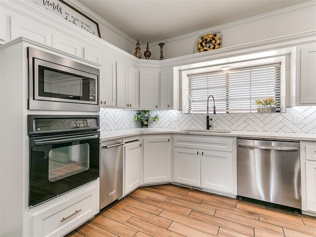 kitchen with tasteful backsplash, light countertops, white cabinetry, stainless steel appliances, and a sink