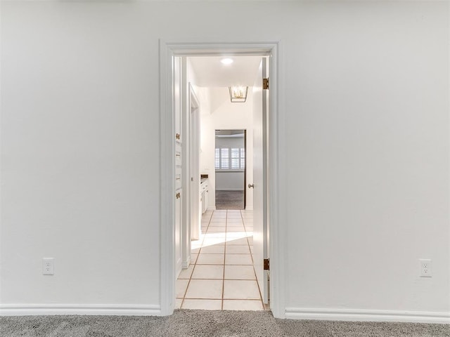corridor featuring baseboards and light tile patterned flooring