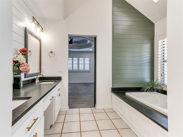 full bathroom featuring a sink, wood walls, tile patterned floors, and a garden tub