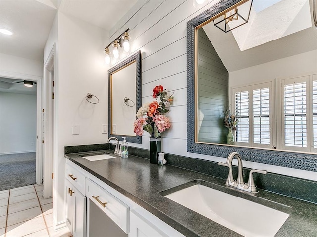 full bathroom featuring a sink, a skylight, double vanity, and tile patterned flooring