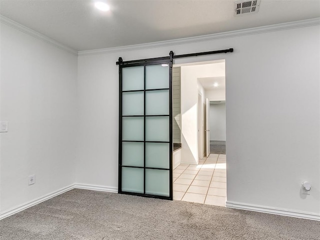 unfurnished room featuring baseboards, ornamental molding, light carpet, a barn door, and visible vents