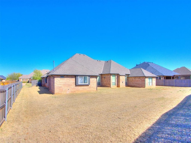 15213 Wilford Way, Edmond, OK 73013 - back of property featuring a yard, brick siding, a fenced backyard, and a shingled roof