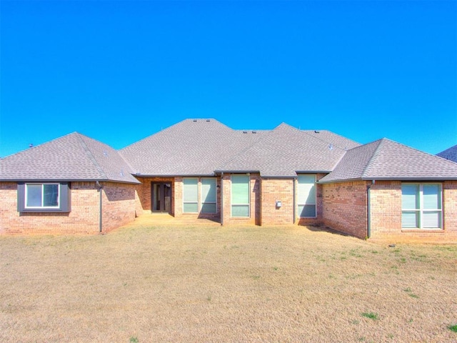 15213 Wilford Way, Edmond, OK 73013 - rear view of house with roof with shingles, brick siding, and a lawn