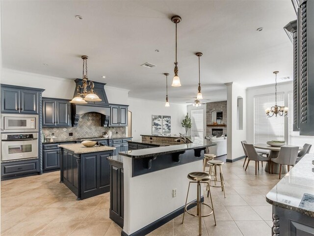 15213 Wilford Way, Edmond, OK 73013 - kitchen featuring white microwave, ceiling fan with notable chandelier, tasteful backsplash, oven, and a spacious island