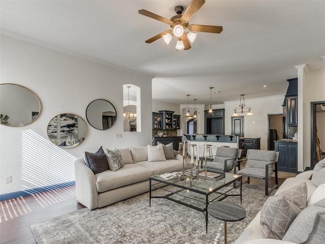 15213 Wilford Way, Edmond, OK 73013 - living room featuring ornamental molding, baseboards, wood finished floors, and ceiling fan with notable chandelier