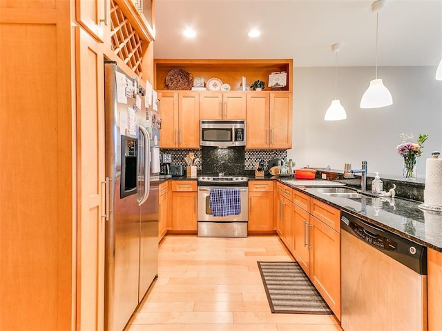 kitchen with tasteful backsplash, dark stone counters, stainless steel appliances, light wood-style floors, and a sink