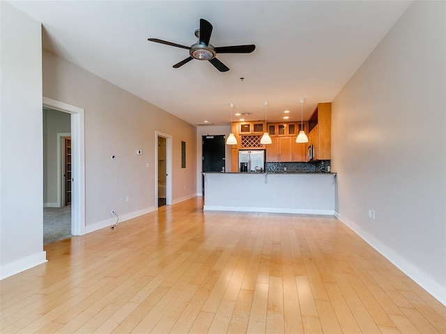 unfurnished living room with baseboards, ceiling fan, and light wood finished floors