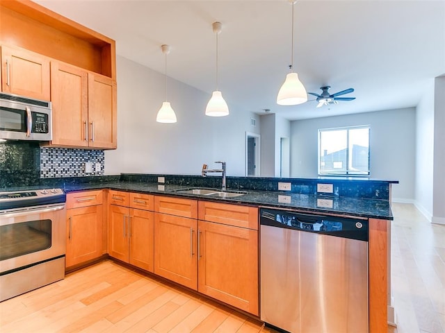 kitchen featuring tasteful backsplash, stainless steel appliances, light wood-style floors, and a sink