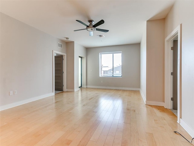 empty room with a ceiling fan, visible vents, light wood-style flooring, and baseboards