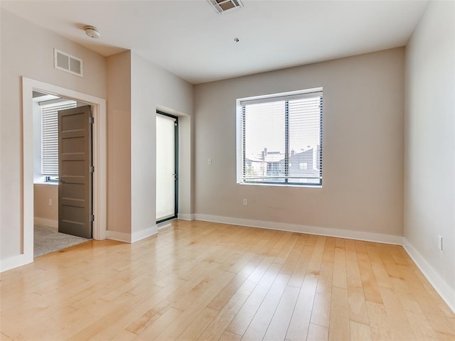 spare room featuring a wealth of natural light, visible vents, light wood finished floors, and baseboards