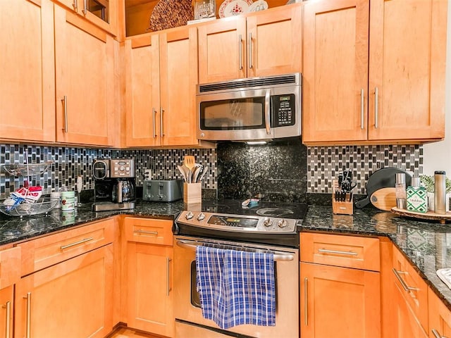 kitchen featuring dark stone countertops, stainless steel appliances, and backsplash