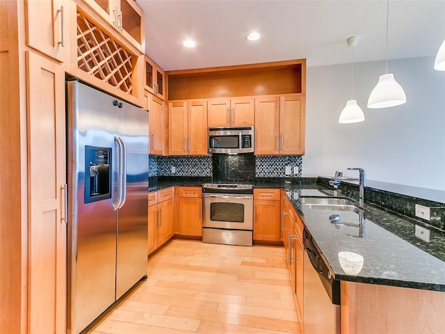 kitchen with a sink, stainless steel appliances, light wood-style floors, tasteful backsplash, and a peninsula