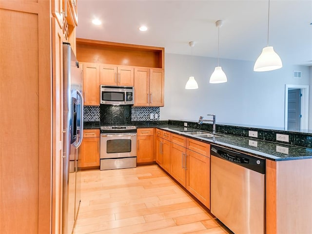 kitchen featuring decorative backsplash, a sink, appliances with stainless steel finishes, light wood-style floors, and a peninsula