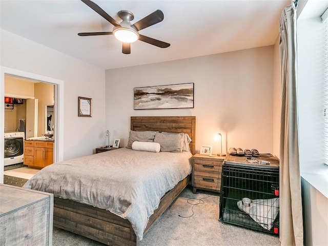 bedroom with ensuite bath, ceiling fan, light colored carpet, and washer / clothes dryer