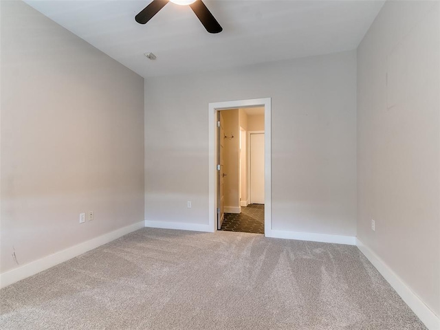 carpeted empty room with a ceiling fan and baseboards