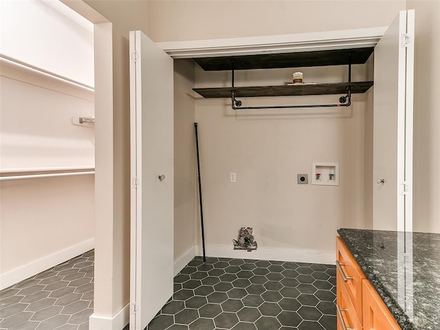 clothes washing area with laundry area, dark tile patterned floors, hookup for an electric dryer, washer hookup, and baseboards
