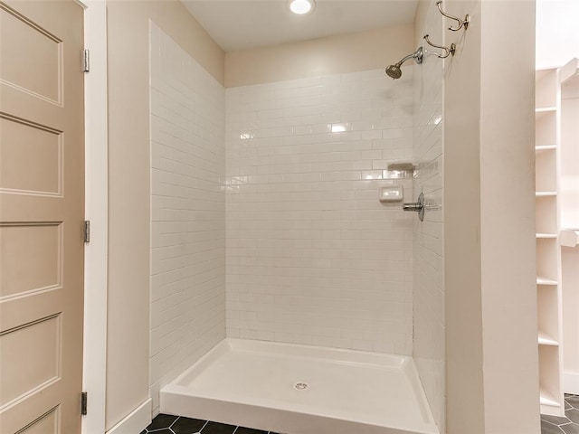 full bath with a stall shower, tile patterned flooring, and baseboards