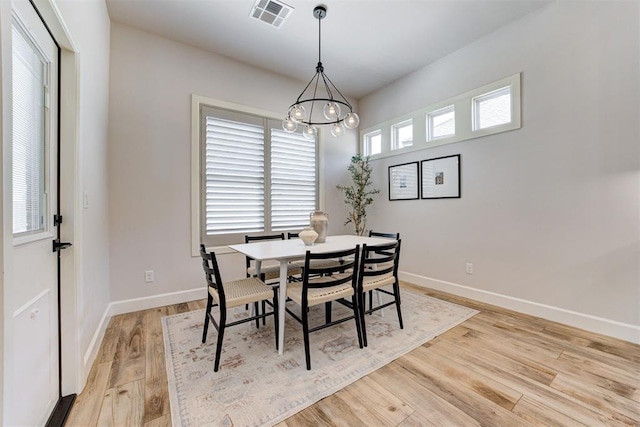 dining area with baseboards, light wood-type flooring, a notable chandelier, and visible vents