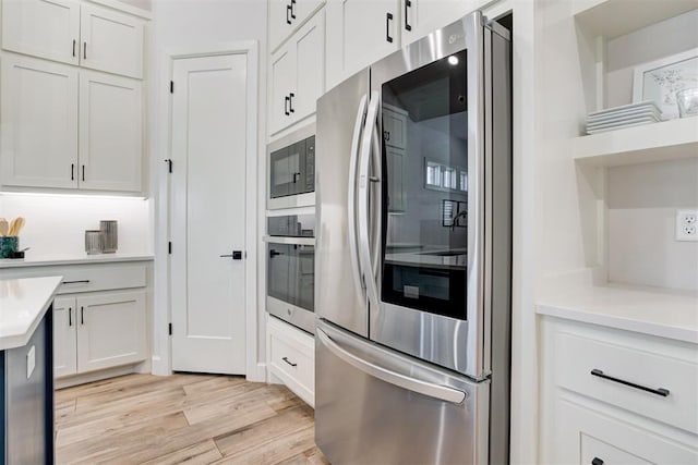 kitchen featuring light countertops, white cabinets, appliances with stainless steel finishes, and light wood finished floors