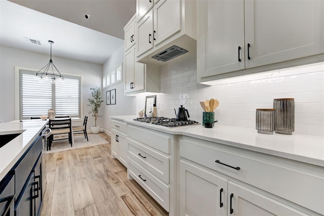 kitchen featuring visible vents, light countertops, a chandelier, stainless steel gas stovetop, and backsplash
